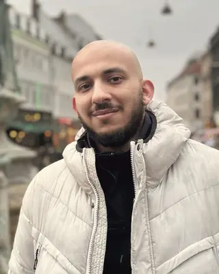 Hanna Filoupatir, souriant, en doudoune blanche dans une rue commerçante